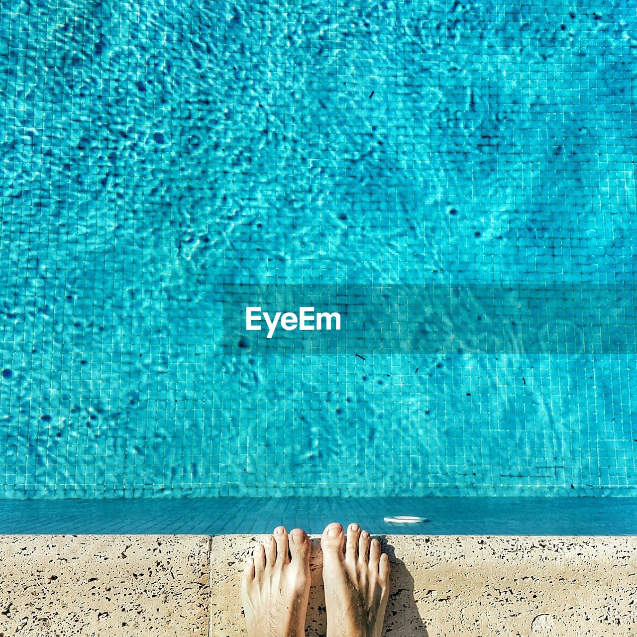 Low section of person standing at poolside