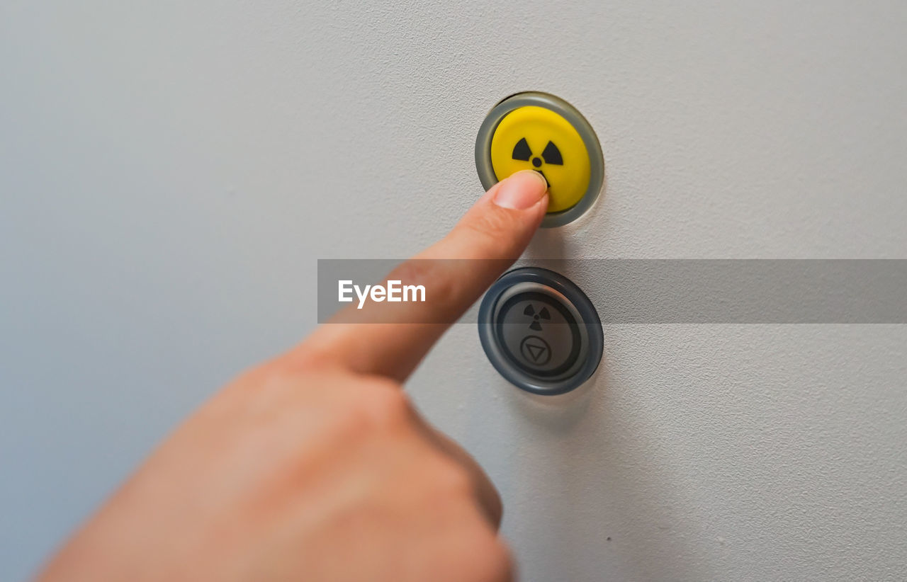 Close-up of hand pressing radioactive warning symbol button 