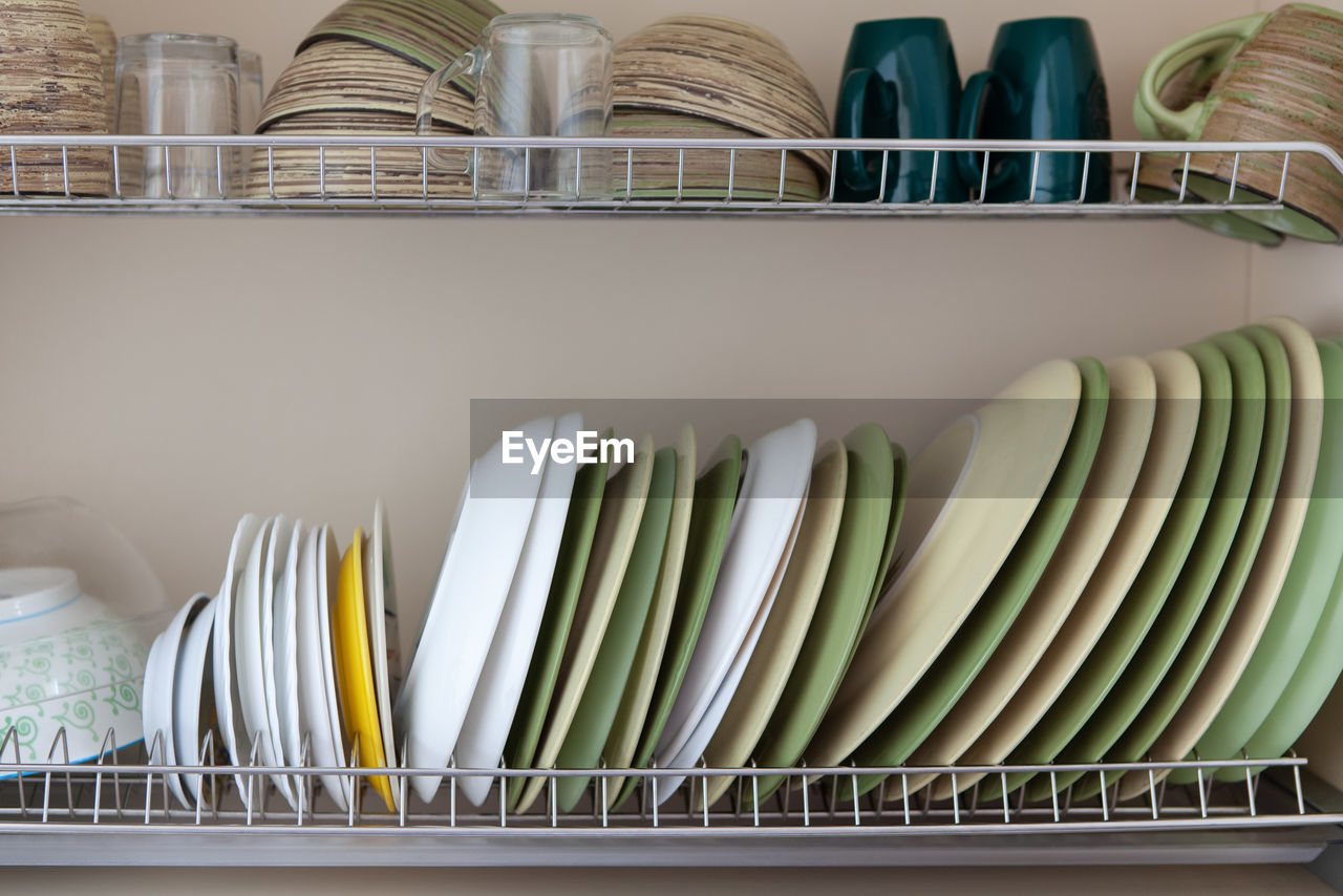 Clean dishes in white and green tones in a drying cabinet. cups, glasses, mugs, plates, bowls