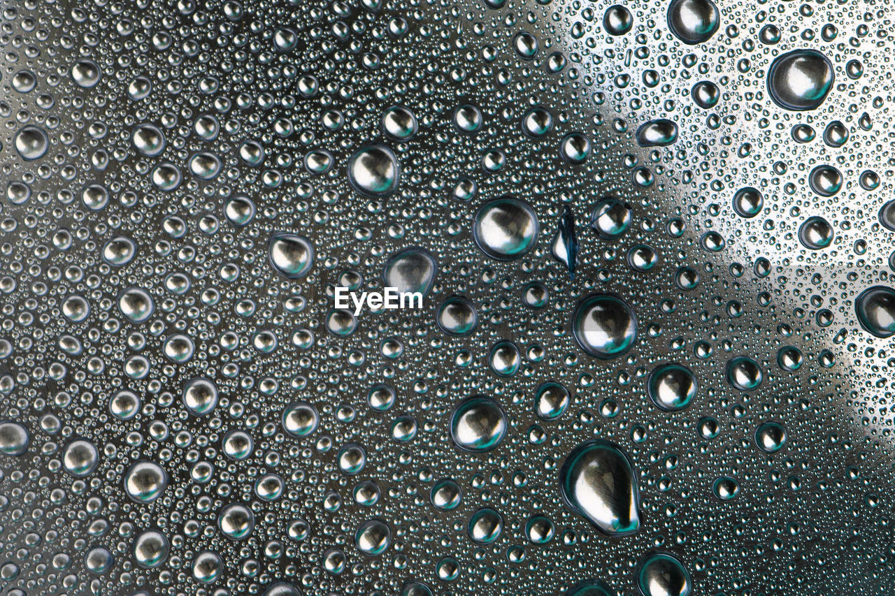 FULL FRAME SHOT OF WET GLASS WITH RAIN DROPS