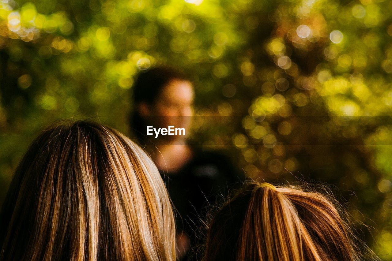 DEFOCUSED IMAGE OF PEOPLE AGAINST TREE