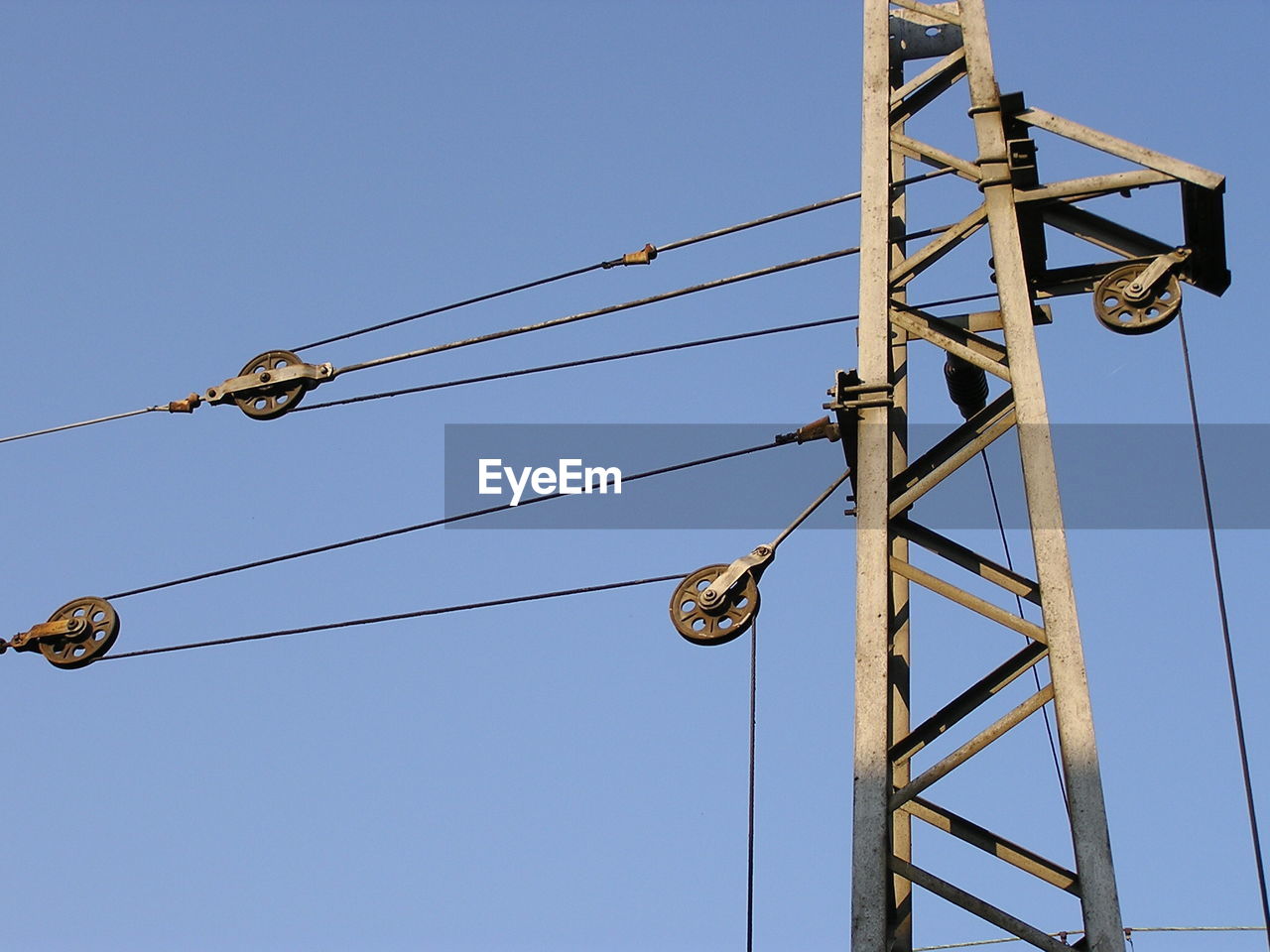 Low angle view of overhead cable car pole against clear sky