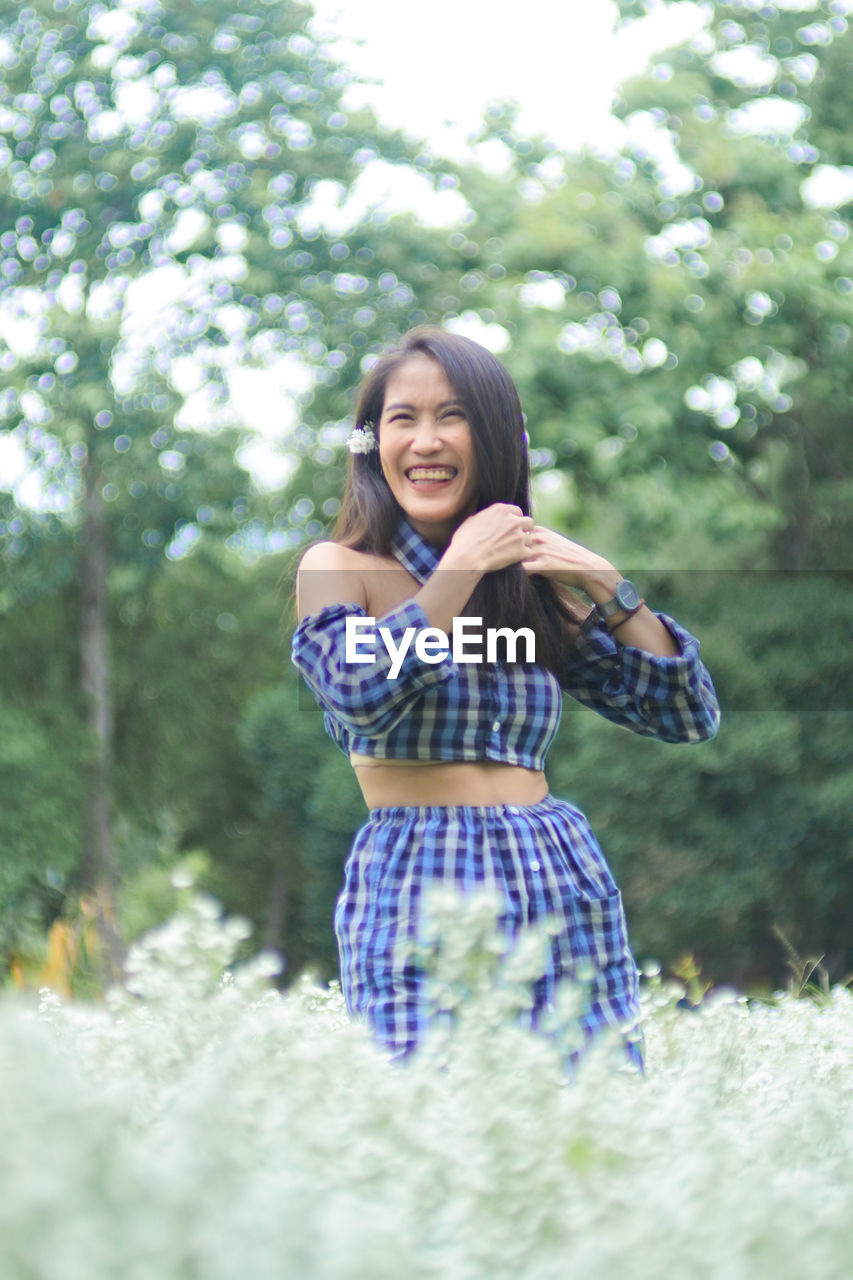 Portrait of a smiling young woman standing against trees