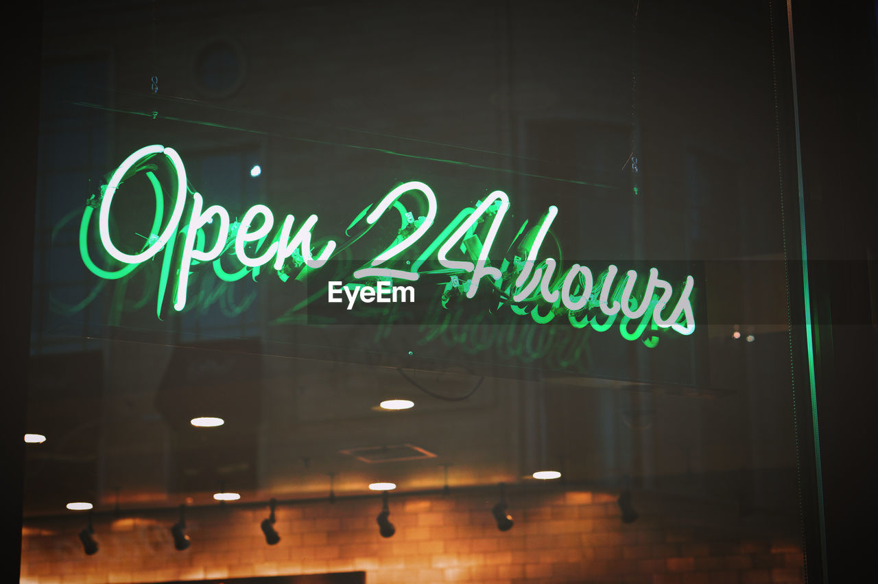 Open 24 hours green neon sign illuminated at night