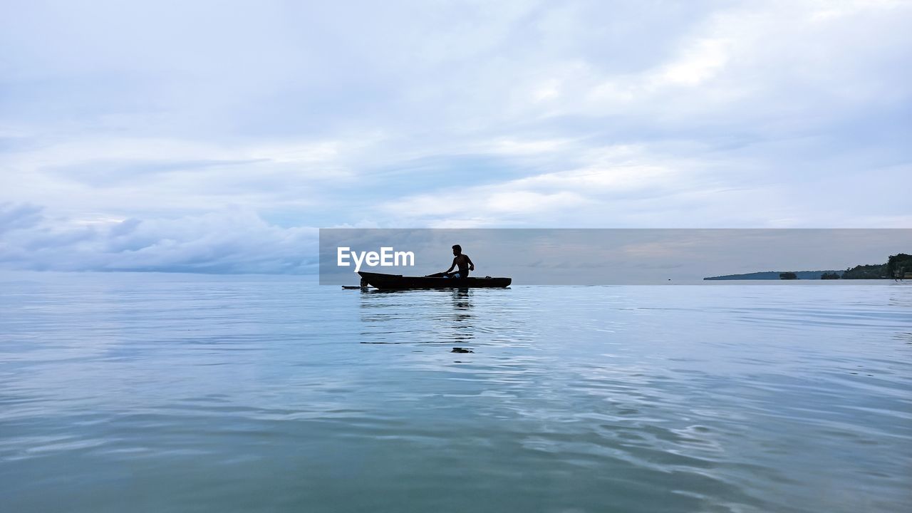 Man on boat in sea against sky