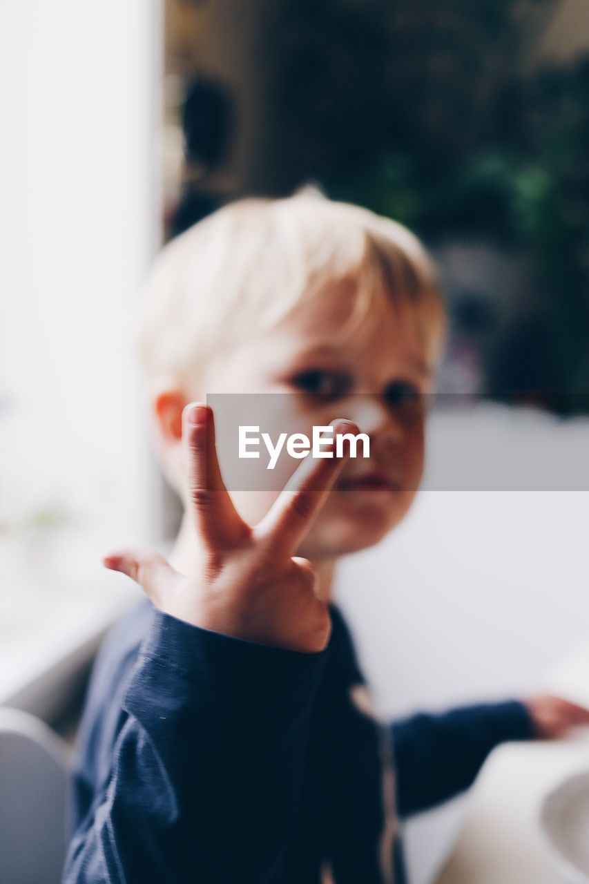 Close-up portrait of cute boy showing peace sign