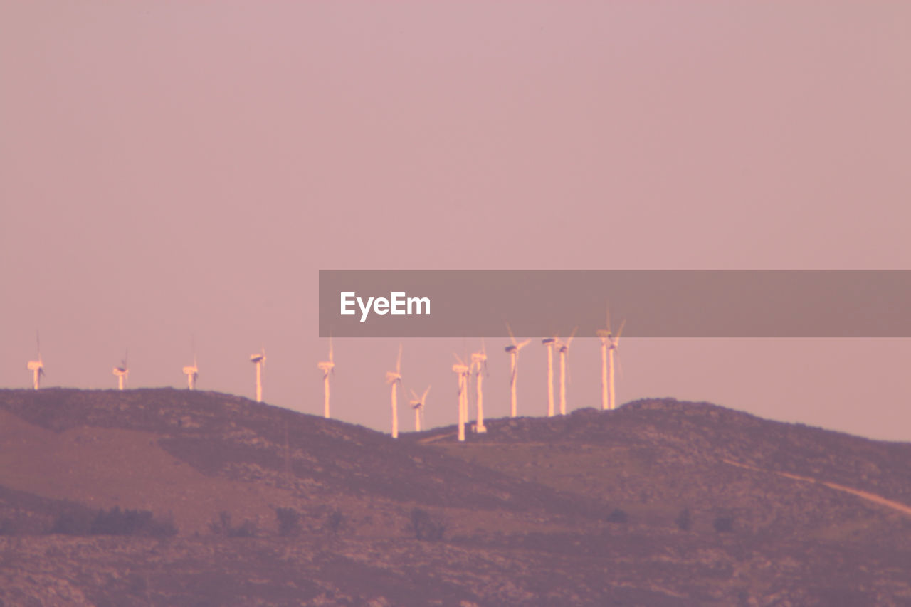 Wind turbines on hills against sky