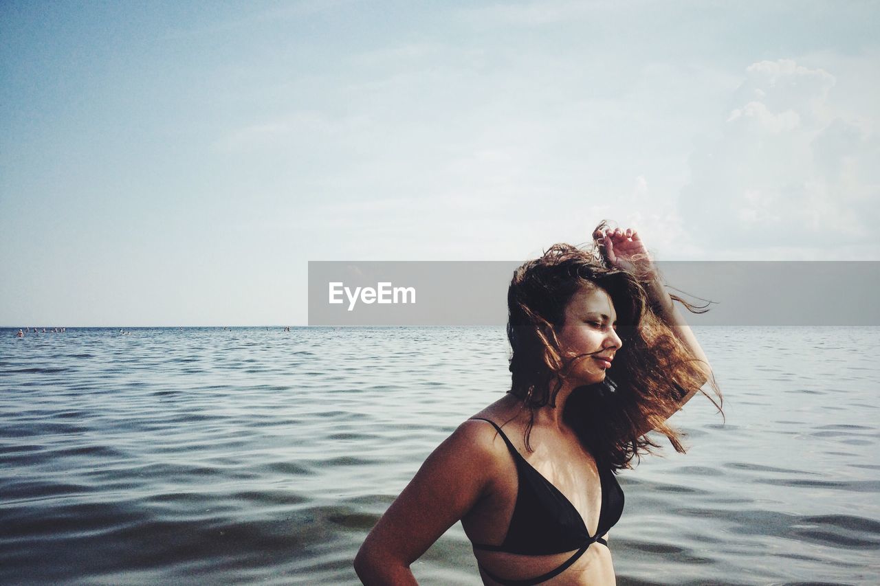 Side view of young woman looking at sea against sky