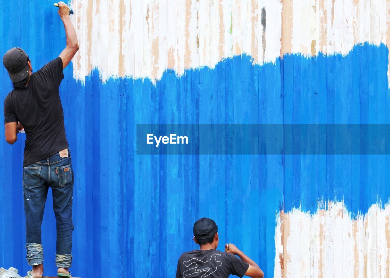 blue, men, wall - building feature, adult, rear view, architecture, person, mural, wood, standing, clothing, day, wall, casual clothing, young adult