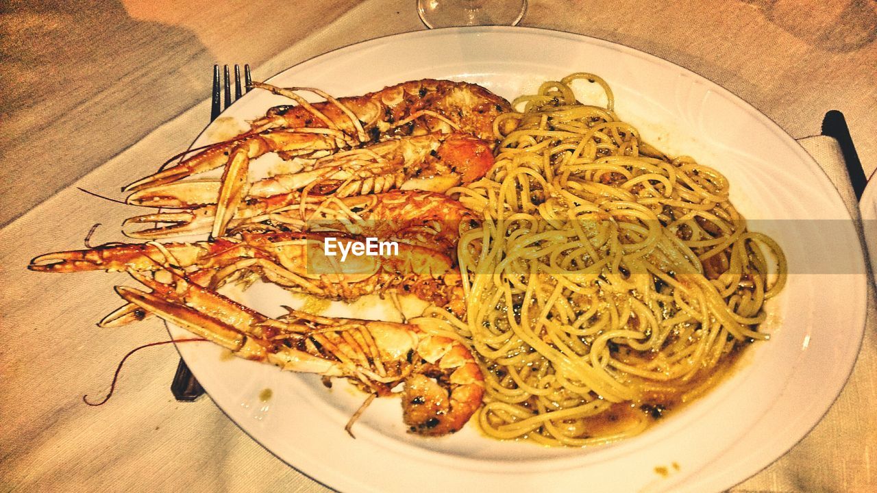 Close-up of buzara shrimp and pasta served in plate on table