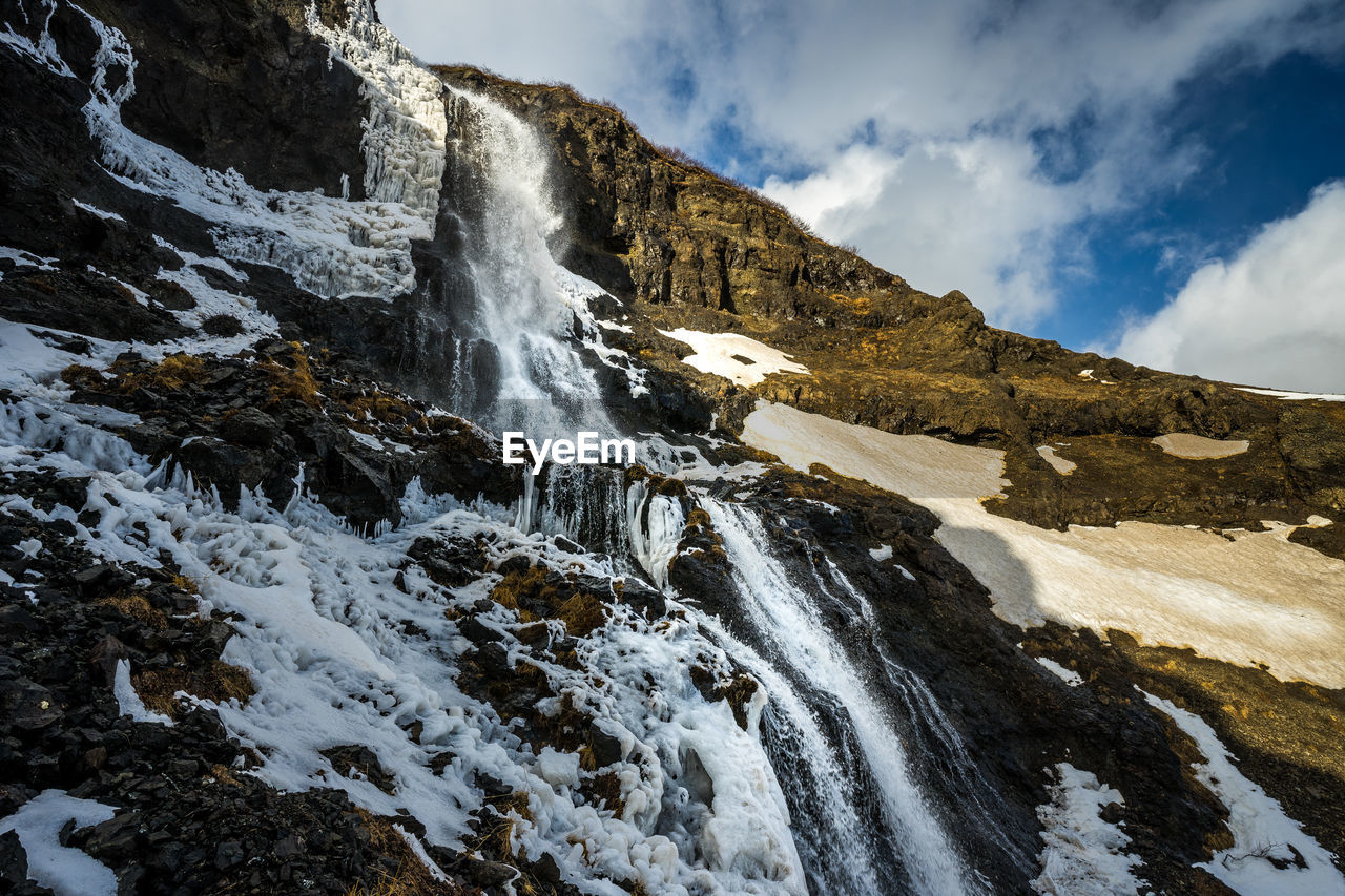 Low angle view of waterfall against sky