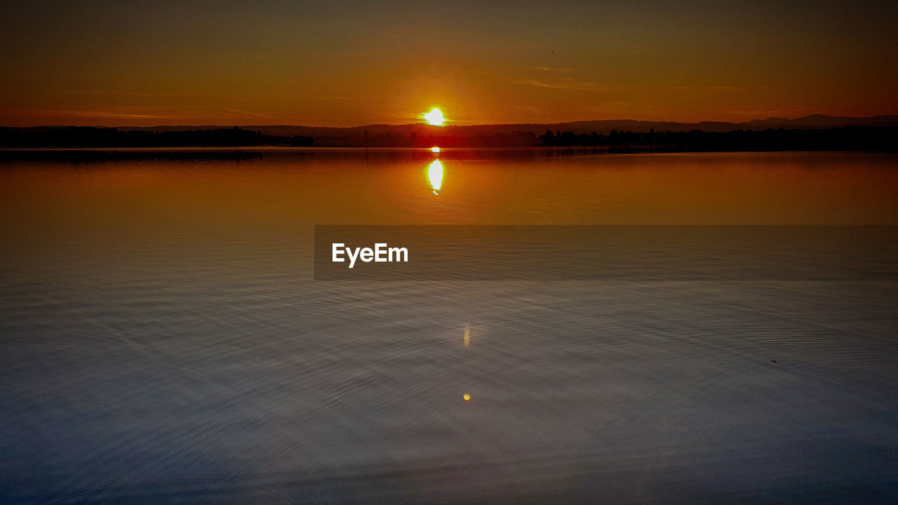 SCENIC VIEW OF LAKE AGAINST ORANGE SKY