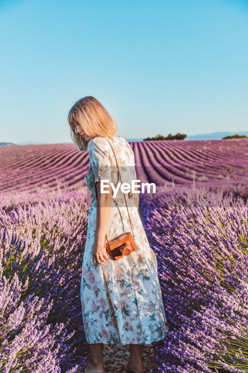 Rear view of woman standing on a lavender field against sky