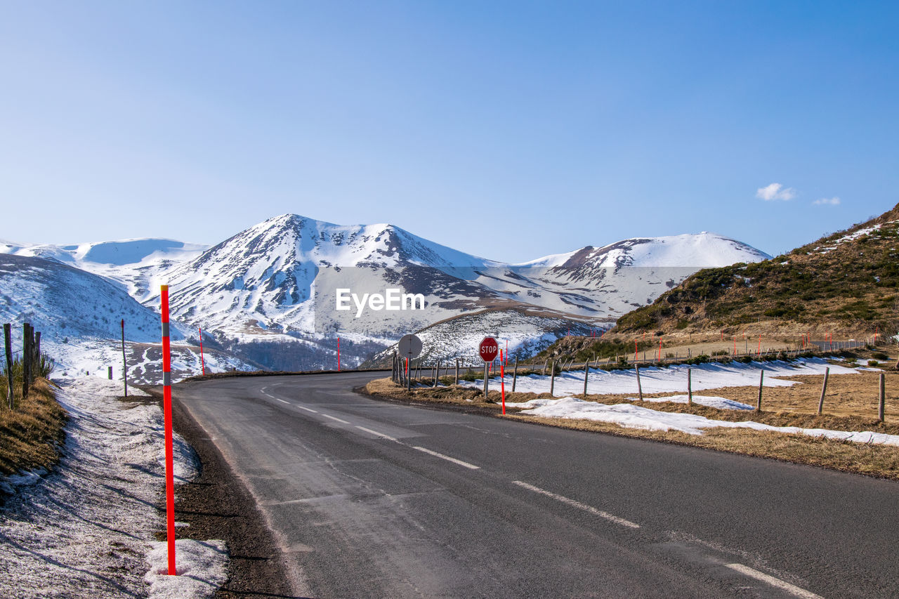 Road by snowcapped mountains against sky