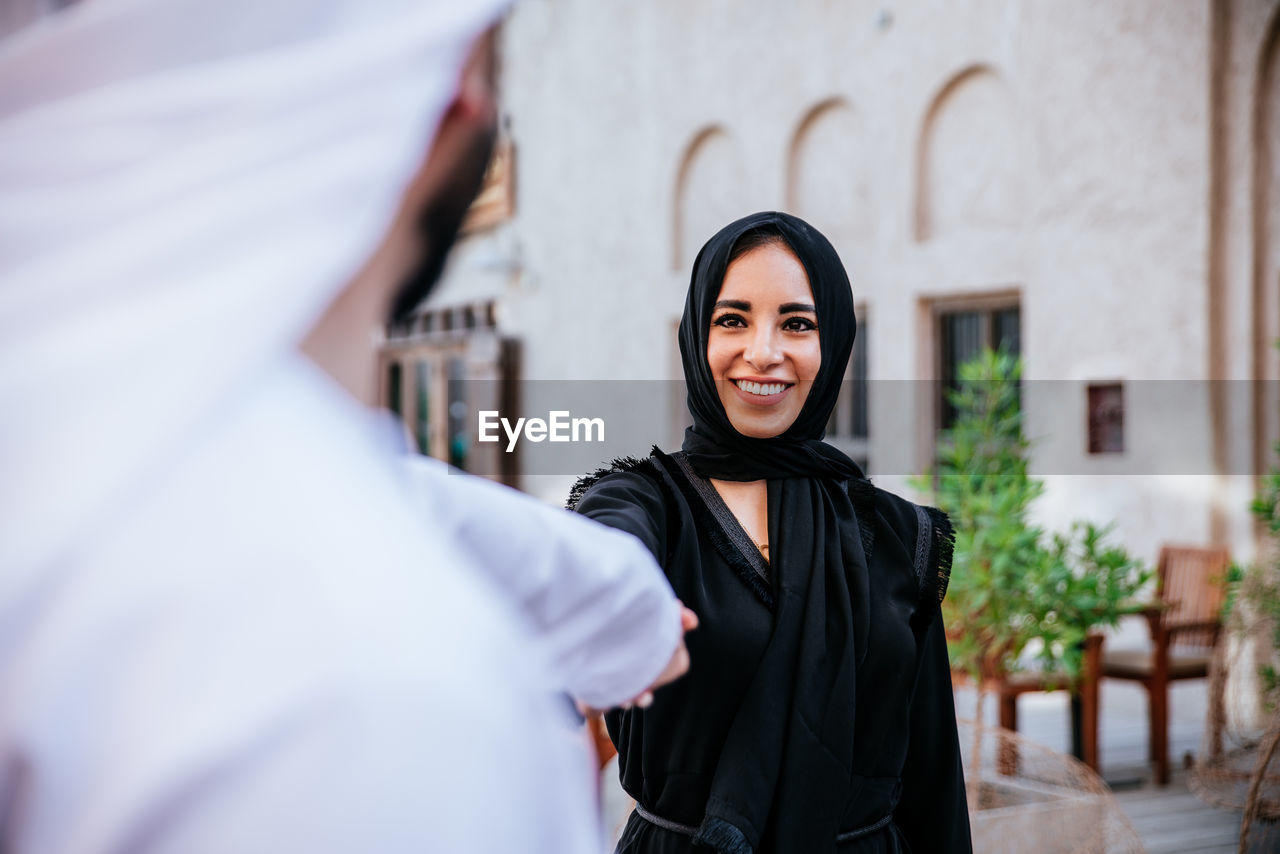 Smiling couple holding hands while standing against building