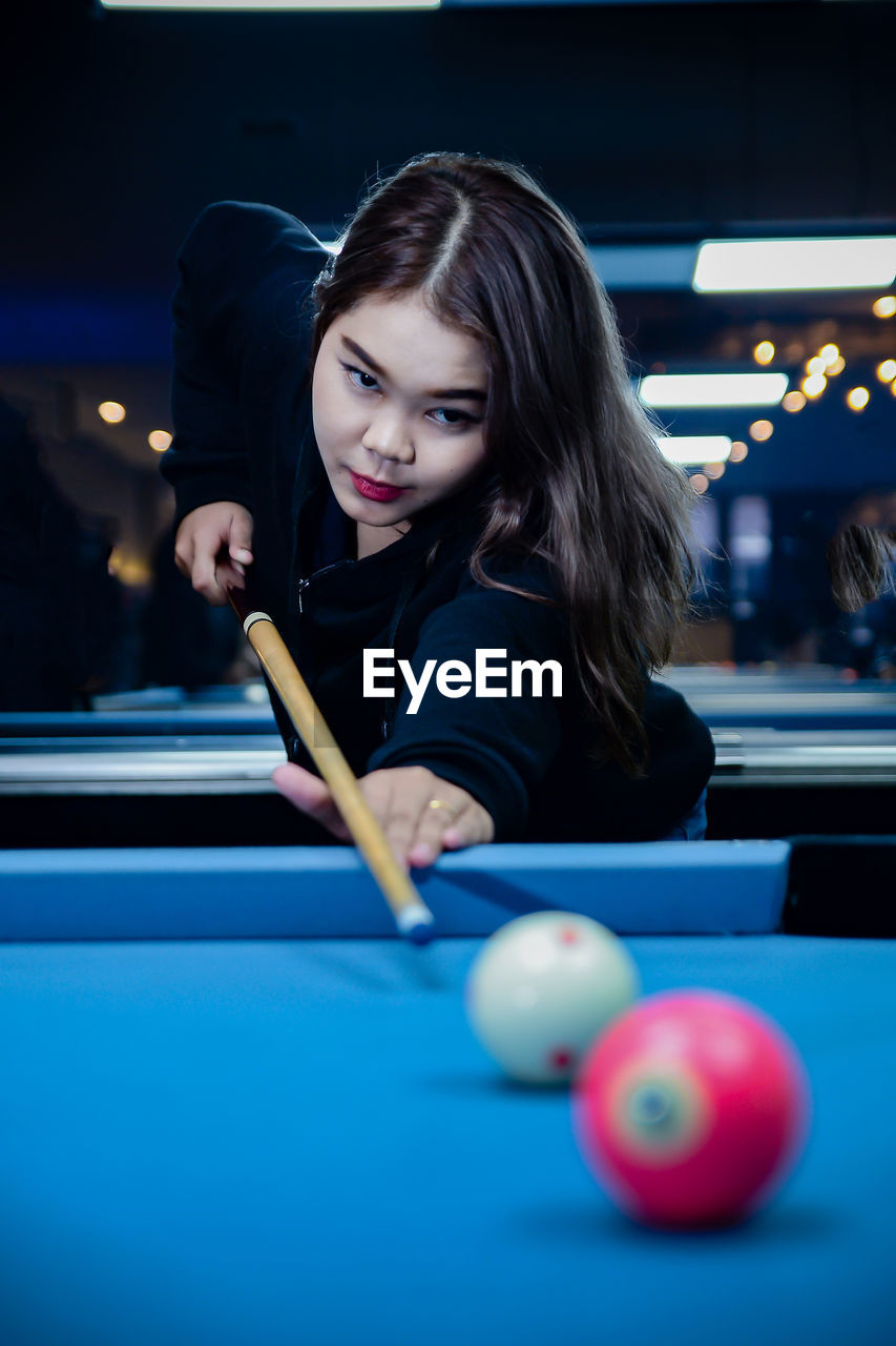 portrait of young woman playing pool at home