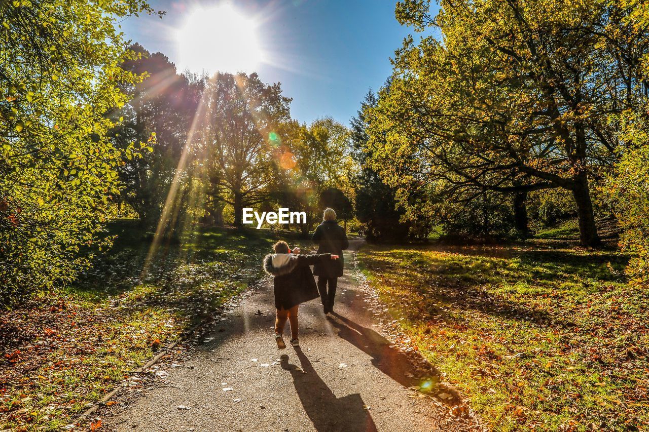 Boy and woman on footpath amidst trees during autumn