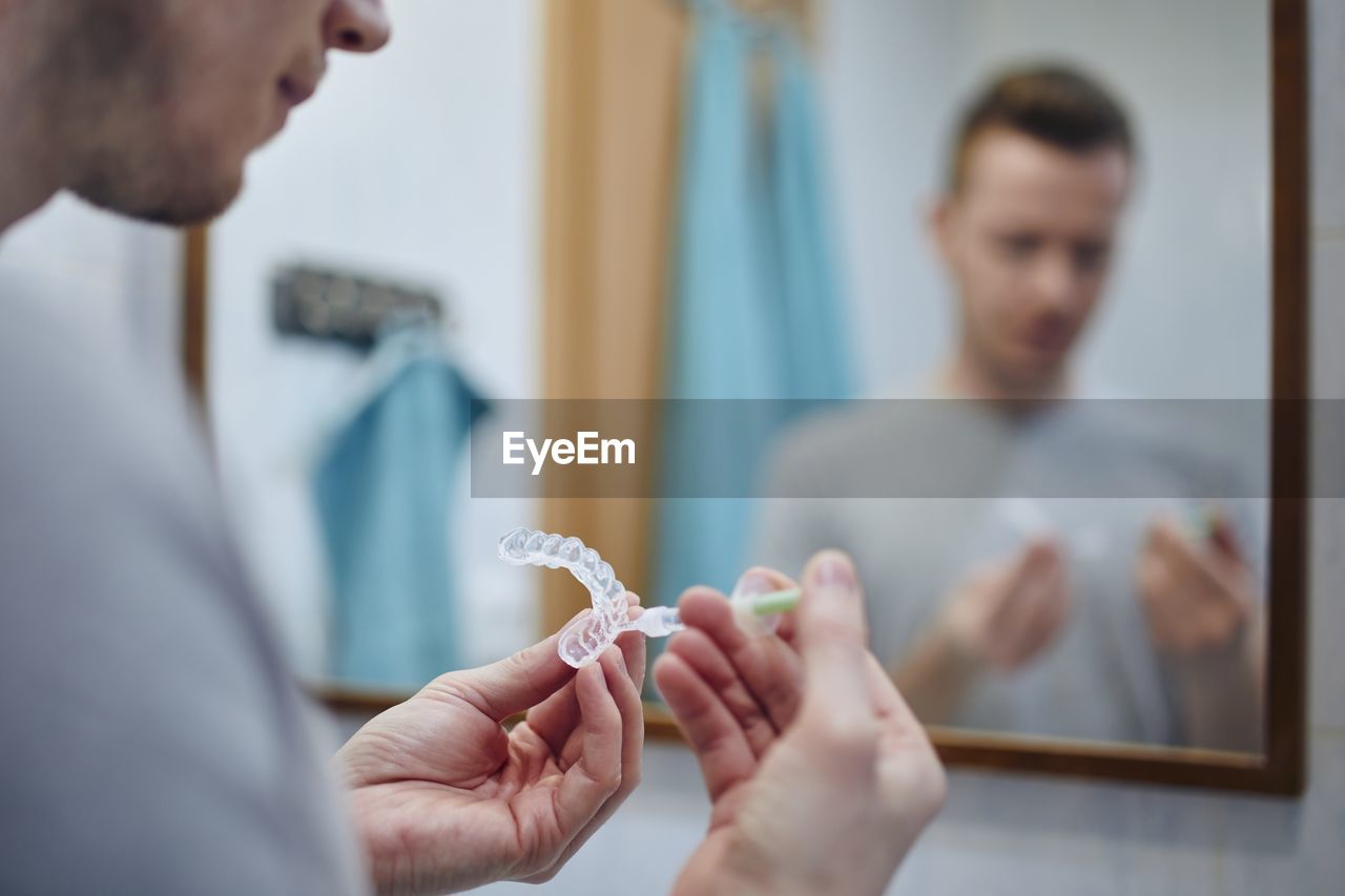 Young man preparing silicon tray for teeth whitening and bleaching gel syringe. 