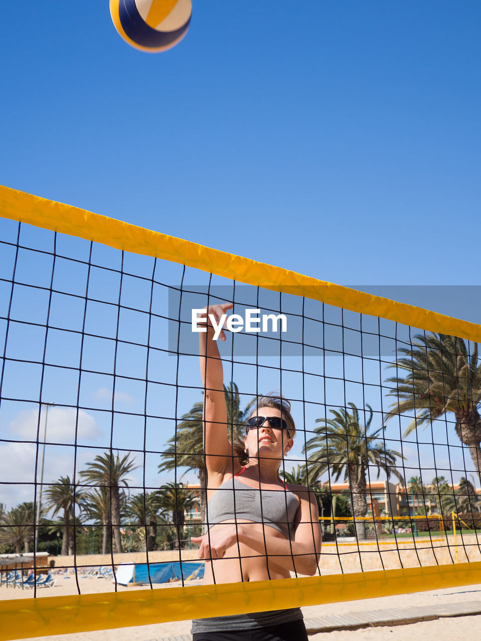 Woman playing volleyball at beach against sky