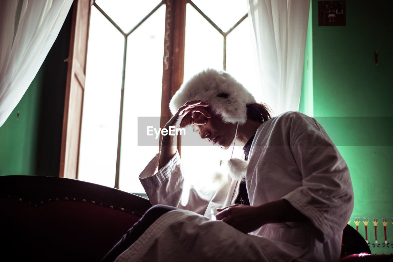 Androgynous woman in alpaca hat sits in window of spanish colonial fla