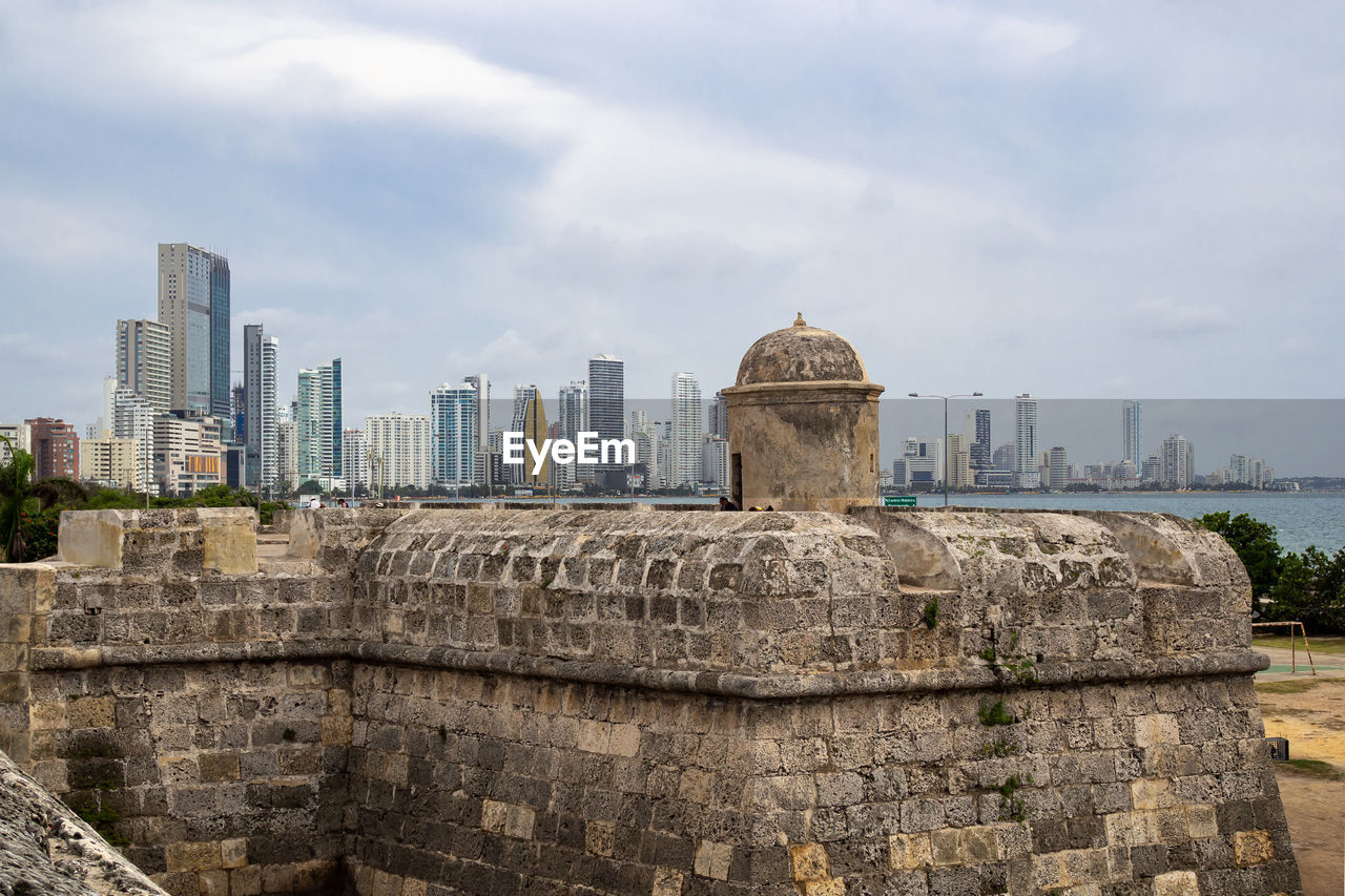 Contrast of ancient structure and modern buildings against sky in city