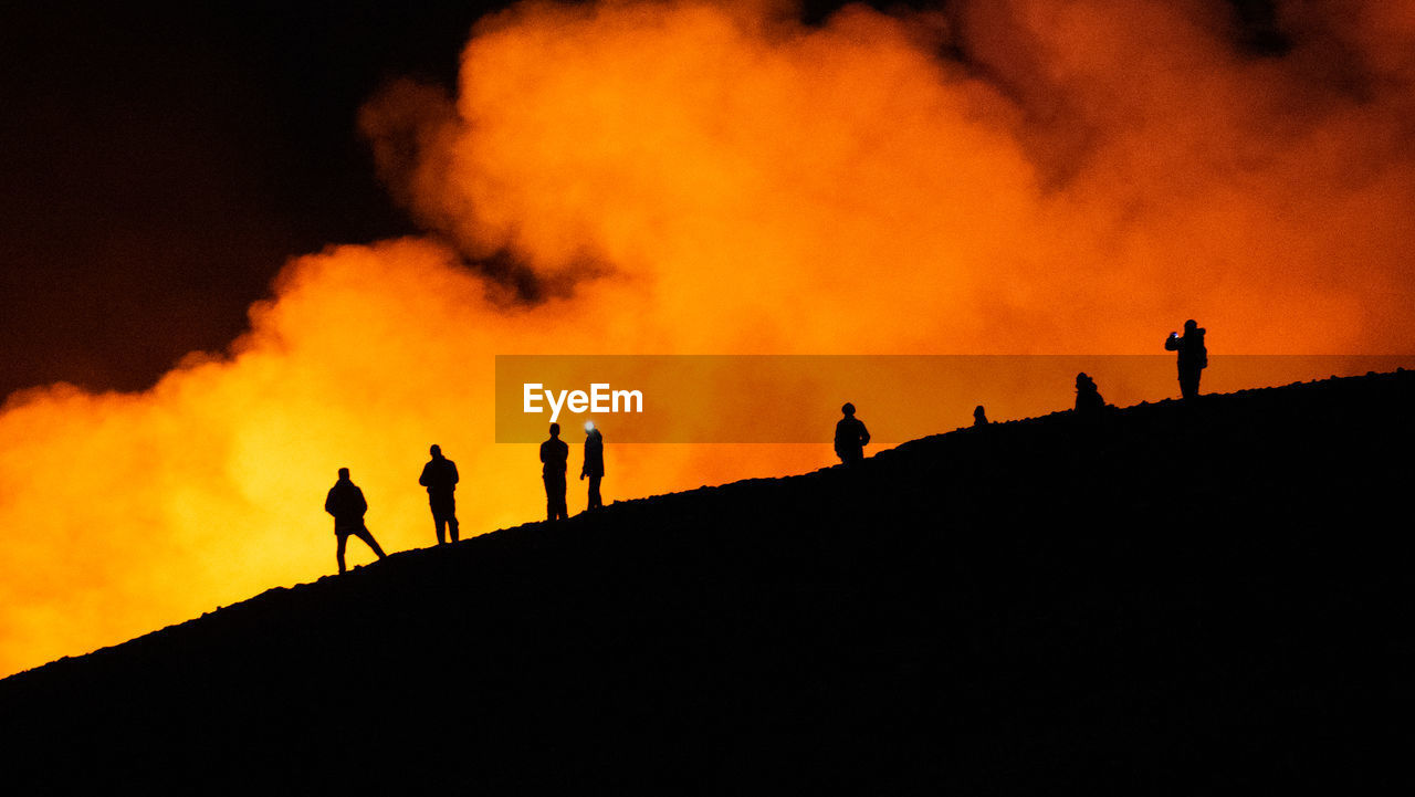 silhouette people standing against fire