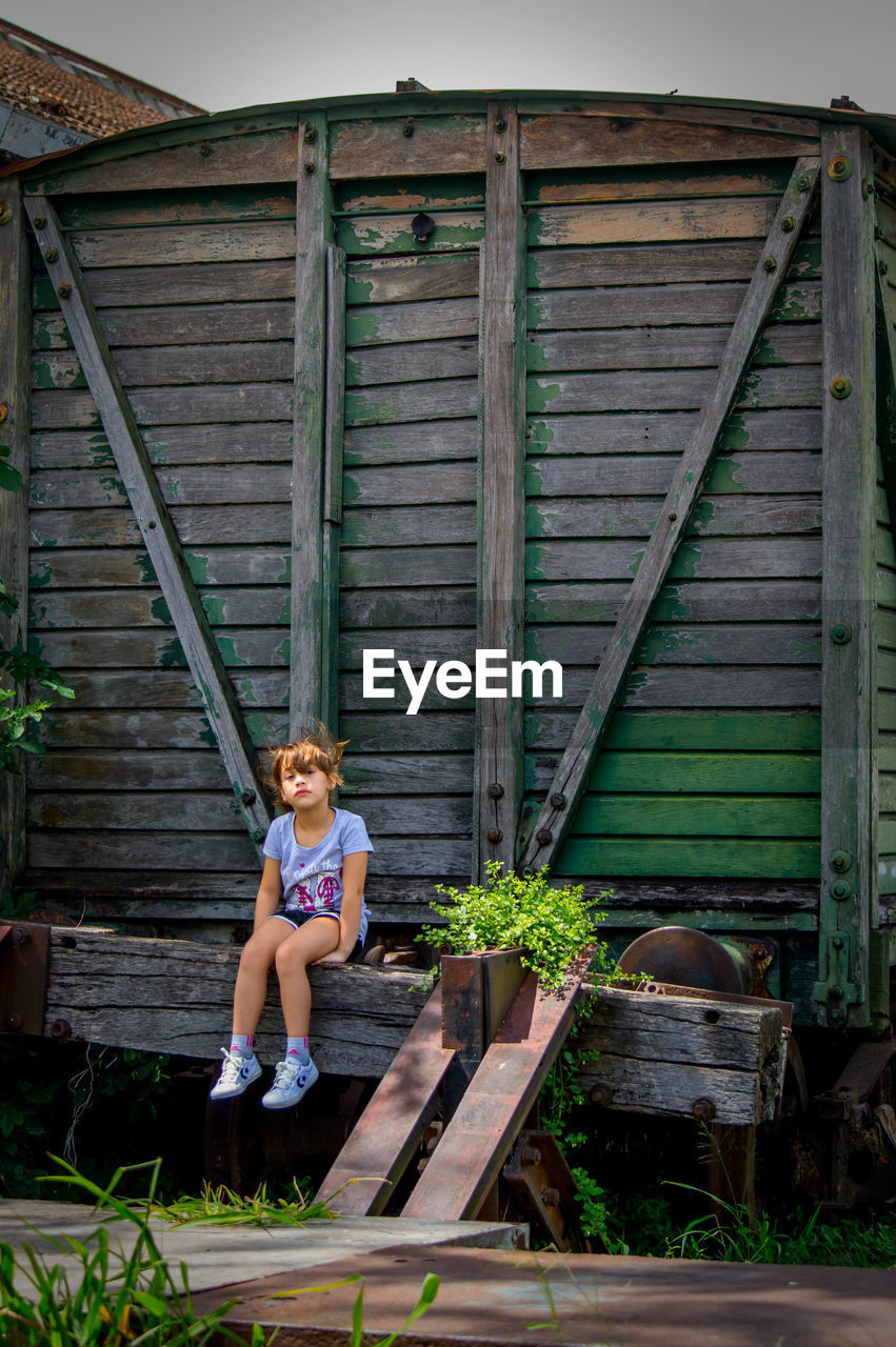 Little blonde girl posing in front of old train wagon