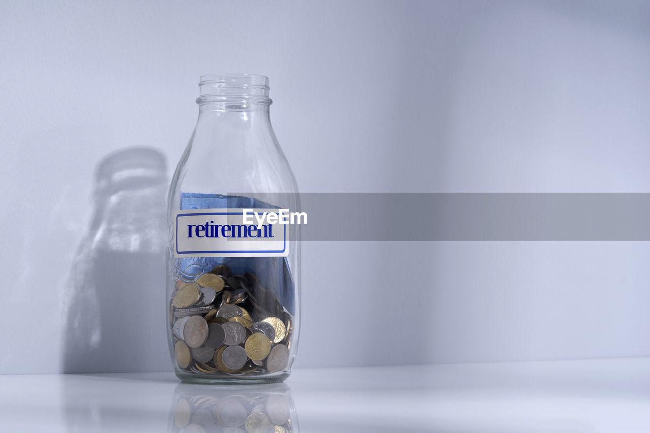 Bottle of saving jar with label retirement on white table top