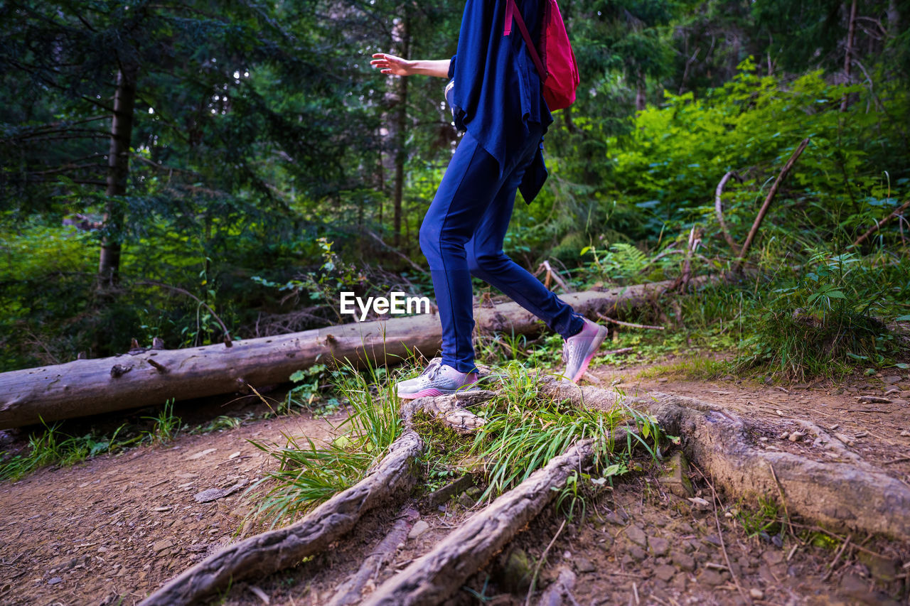 Woman hiker legs wearing sports shoes hiking in woods or forest with backpack adventure lifestyle