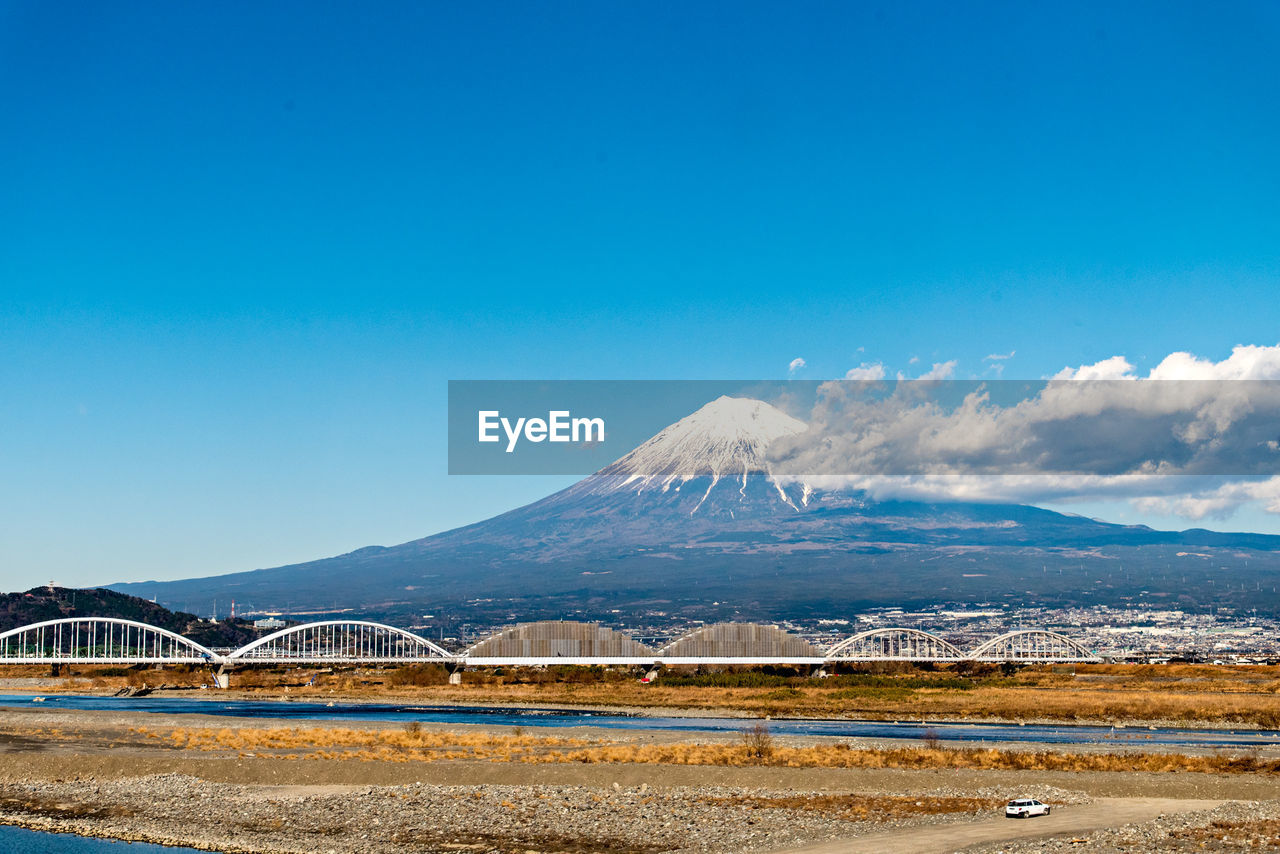 Scenic view of lake by mountains against blue sky