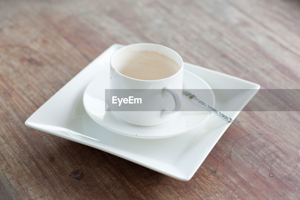 food and drink, mug, cup, drink, crockery, saucer, coffee cup, coffee, table, refreshment, wood, hot drink, indoors, serveware, food, tableware, cappuccino, tea cup, tea, spoon, no people, freshness, cafe, eating utensil, kitchen utensil, white, still life, high angle view, close-up, ceramic