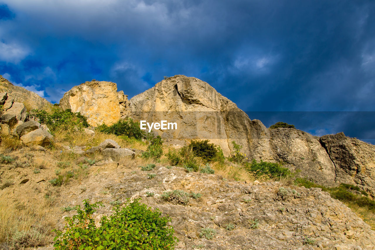 Low angle view of rocks on mountain against sky