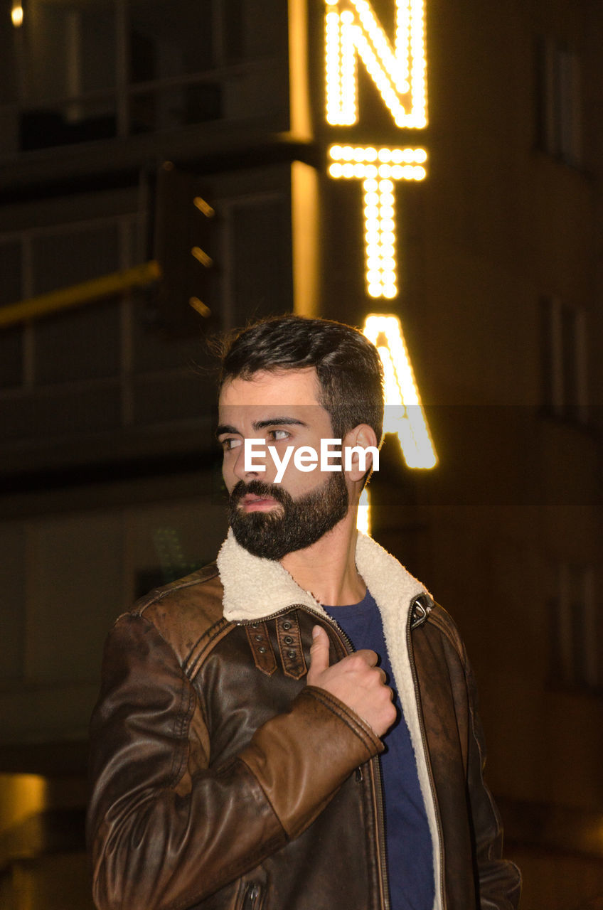 Young man standing in city at night