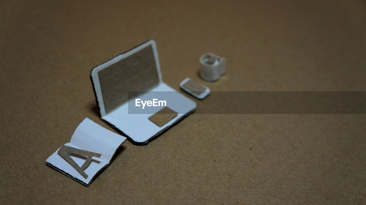 High angle view of artificial laptop with book and cell phone on table