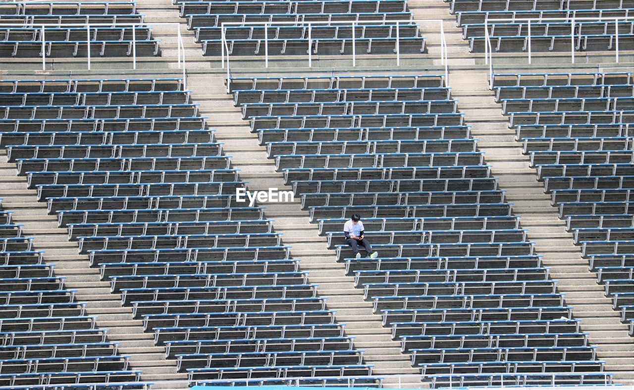 High angle view of man sitting in empty stadium