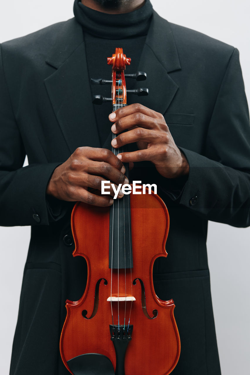 midsection of businessman playing violin against white background