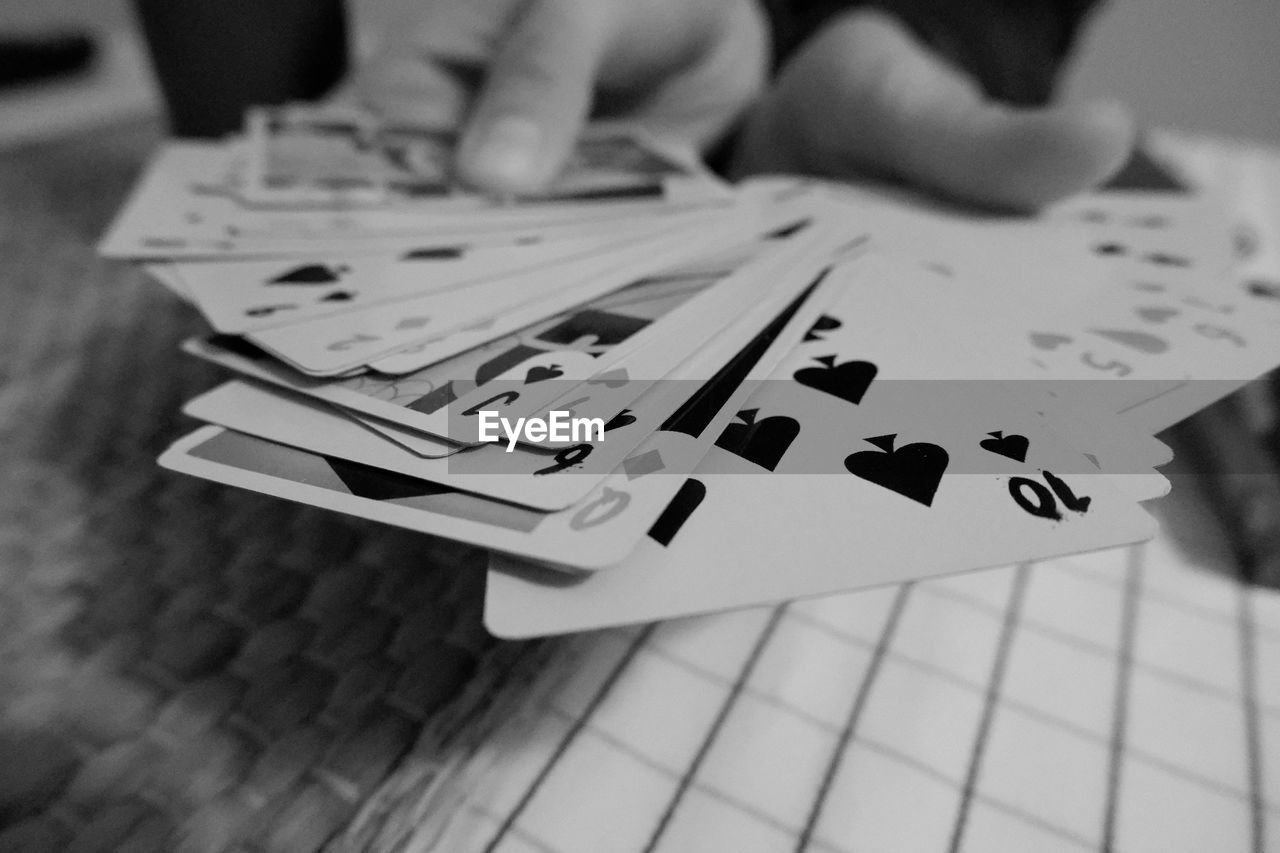 Close-up of person hands holding playing cards on table