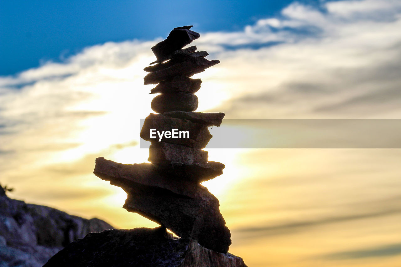 CLOSE-UP OF STACK OF PEBBLES ON ROCK AGAINST SKY