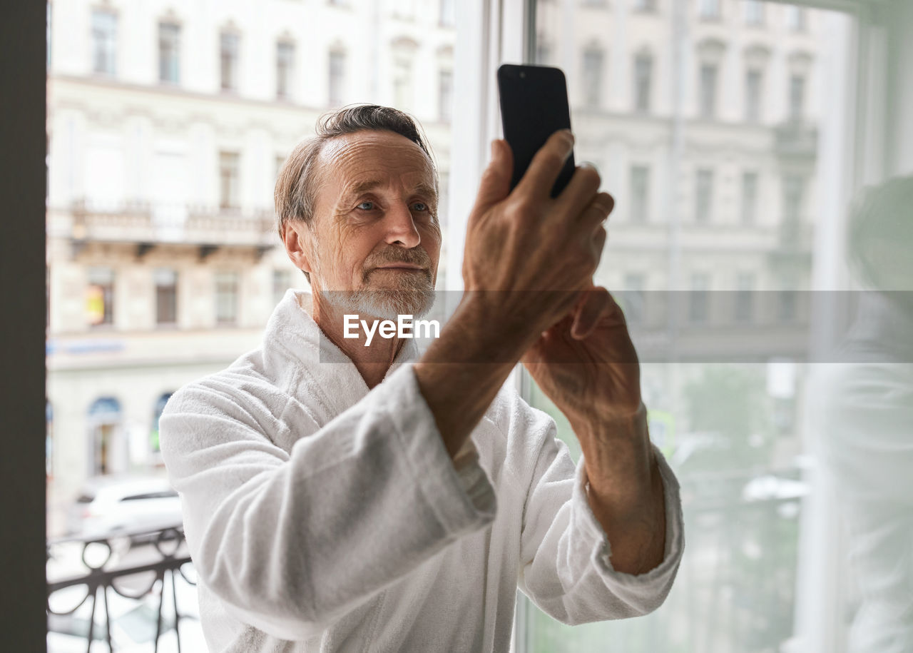 MAN PHOTOGRAPHING WITH MOBILE PHONE IN OFFICE