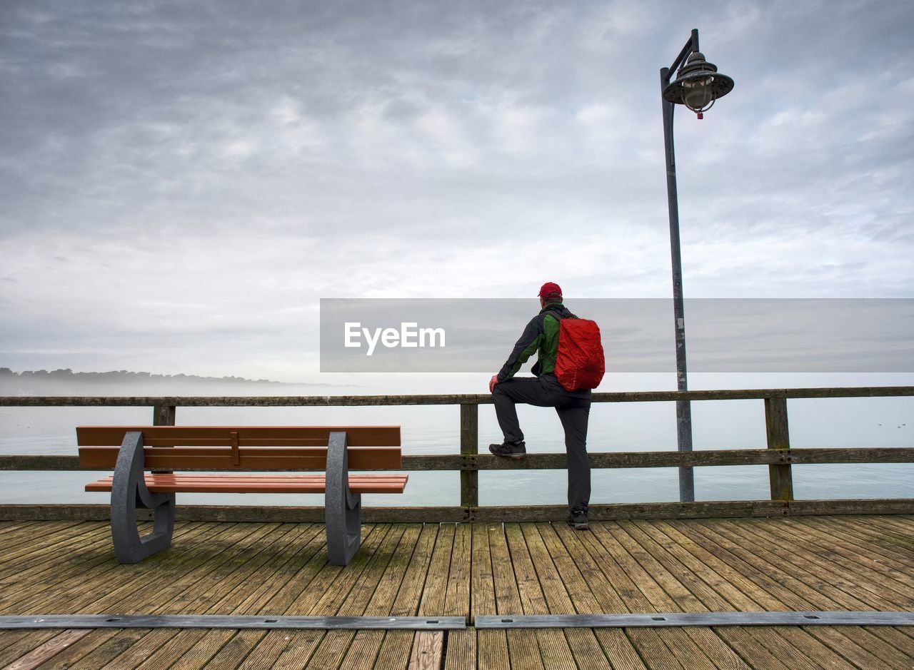 Man sitting on bench by wooden pier and watch calm sea. seabridge on ruegen island