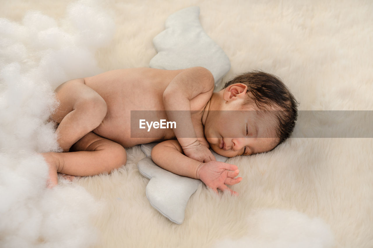 High angle view of naked baby boy sleeping on bed