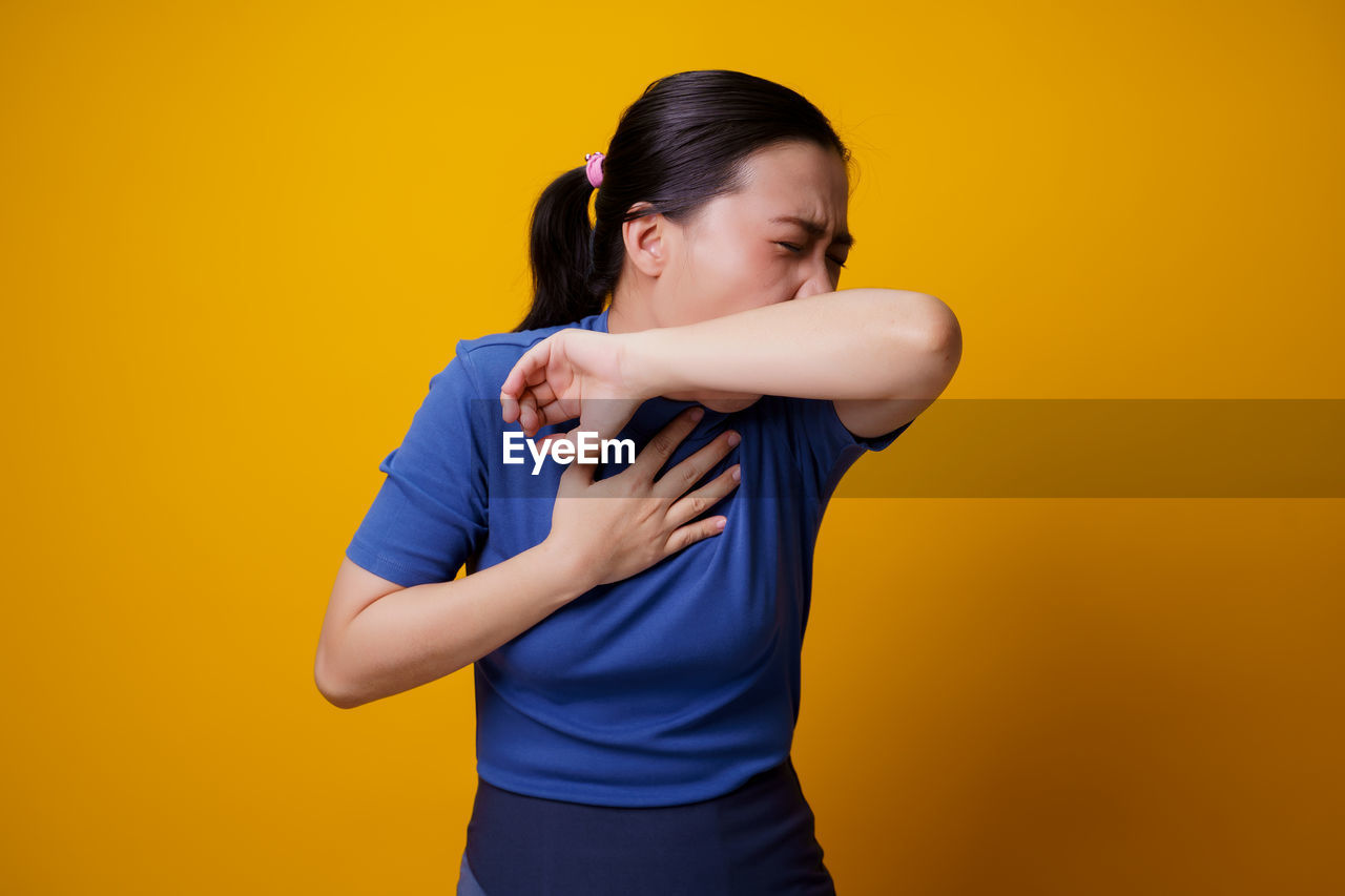 WOMAN STANDING AGAINST YELLOW WALL