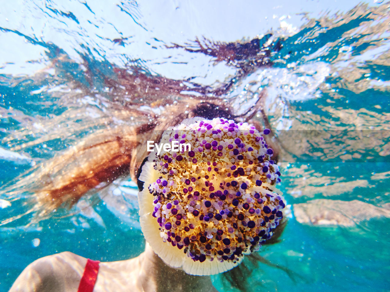 Unrecognizable young woman in diving mask swimming in deep transparent sea water and exploring jellyfish