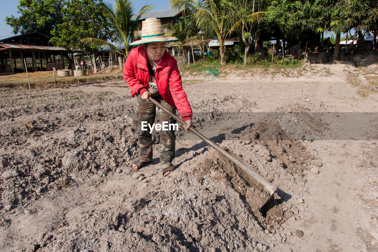 Full length of female farmer wearing hat while working in farm