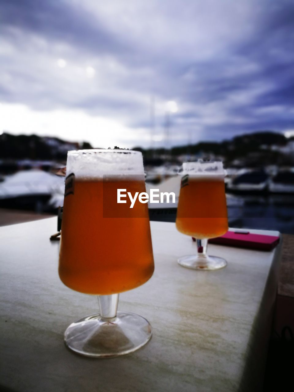 CLOSE-UP OF BEER IN GLASS ON TABLE AGAINST SKY