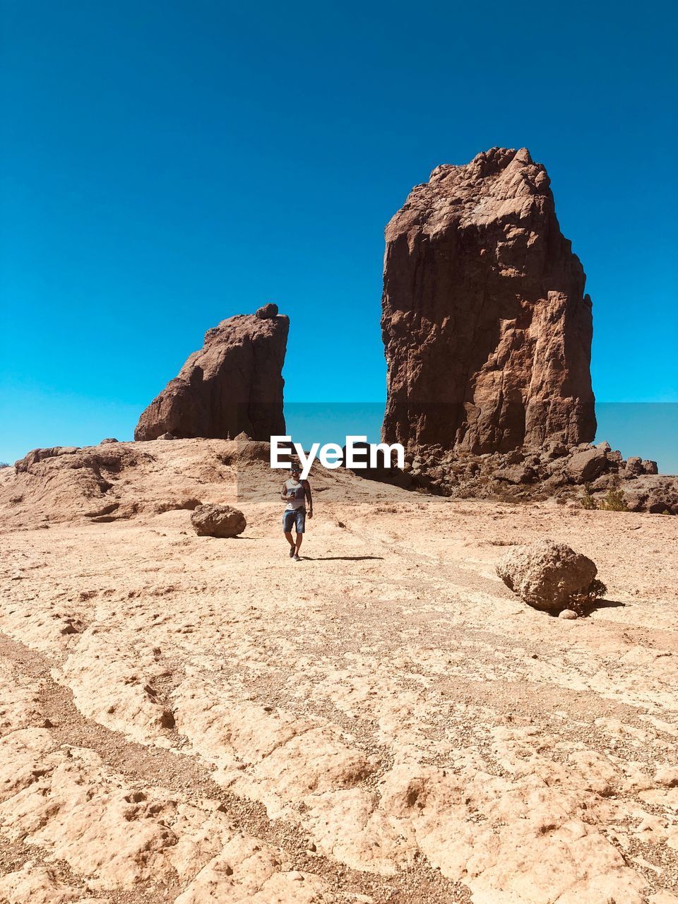 Man walking on land against clear blue sky