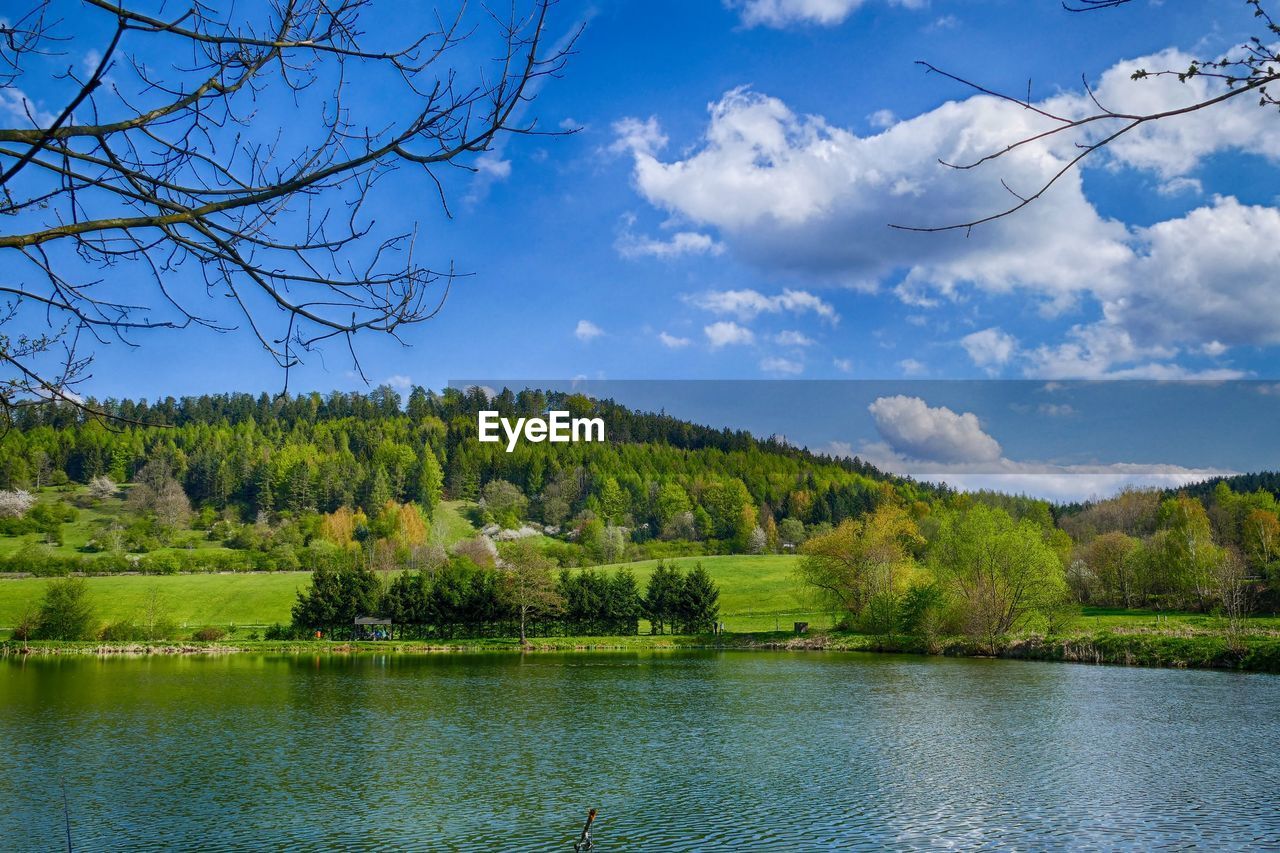 Scenic view of lake and green mountains against blue sky