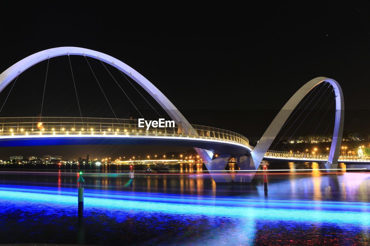 ILLUMINATED BRIDGE OVER RIVER AGAINST SKY