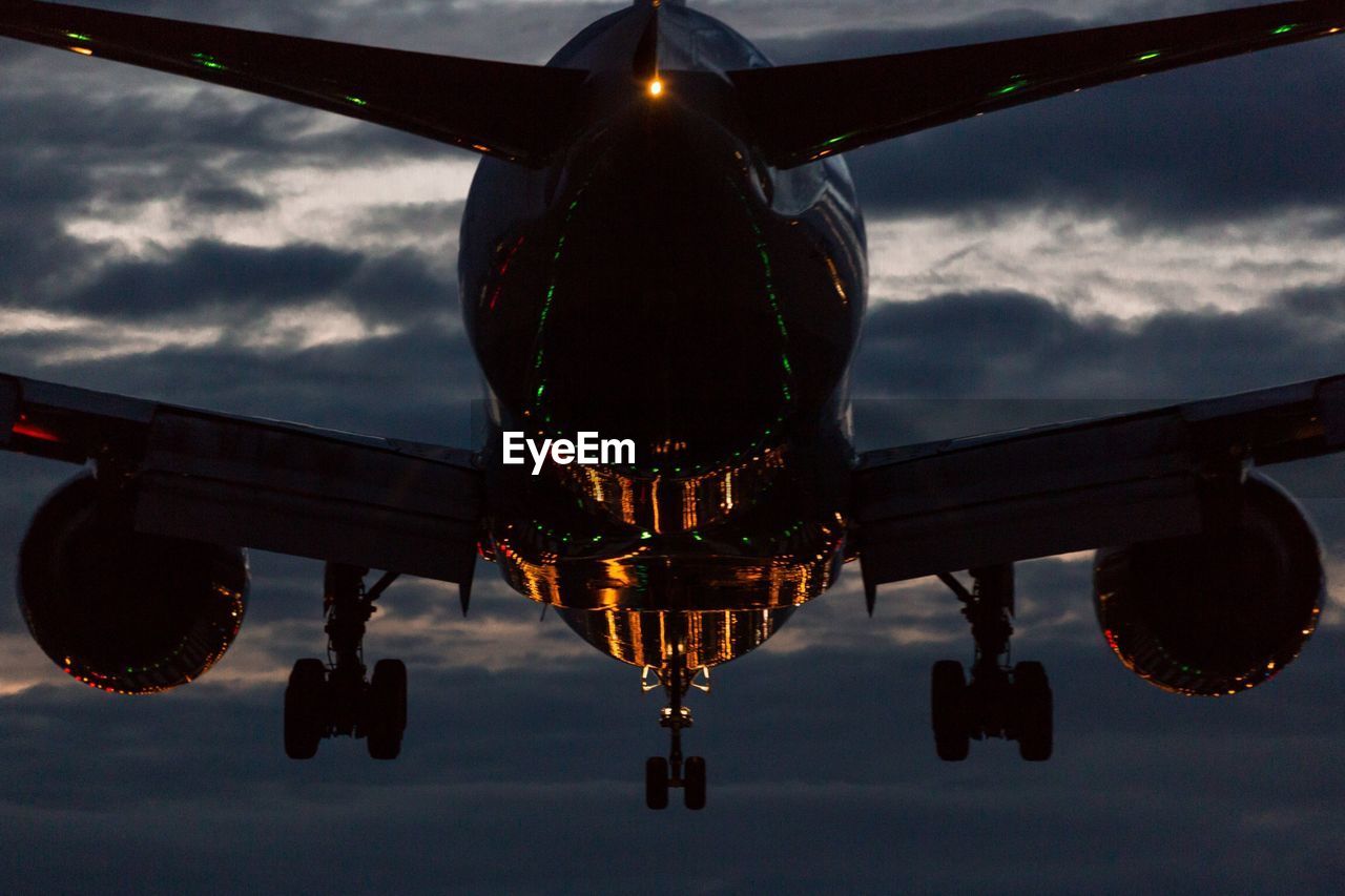 Airplane flying over lake against sky at dusk