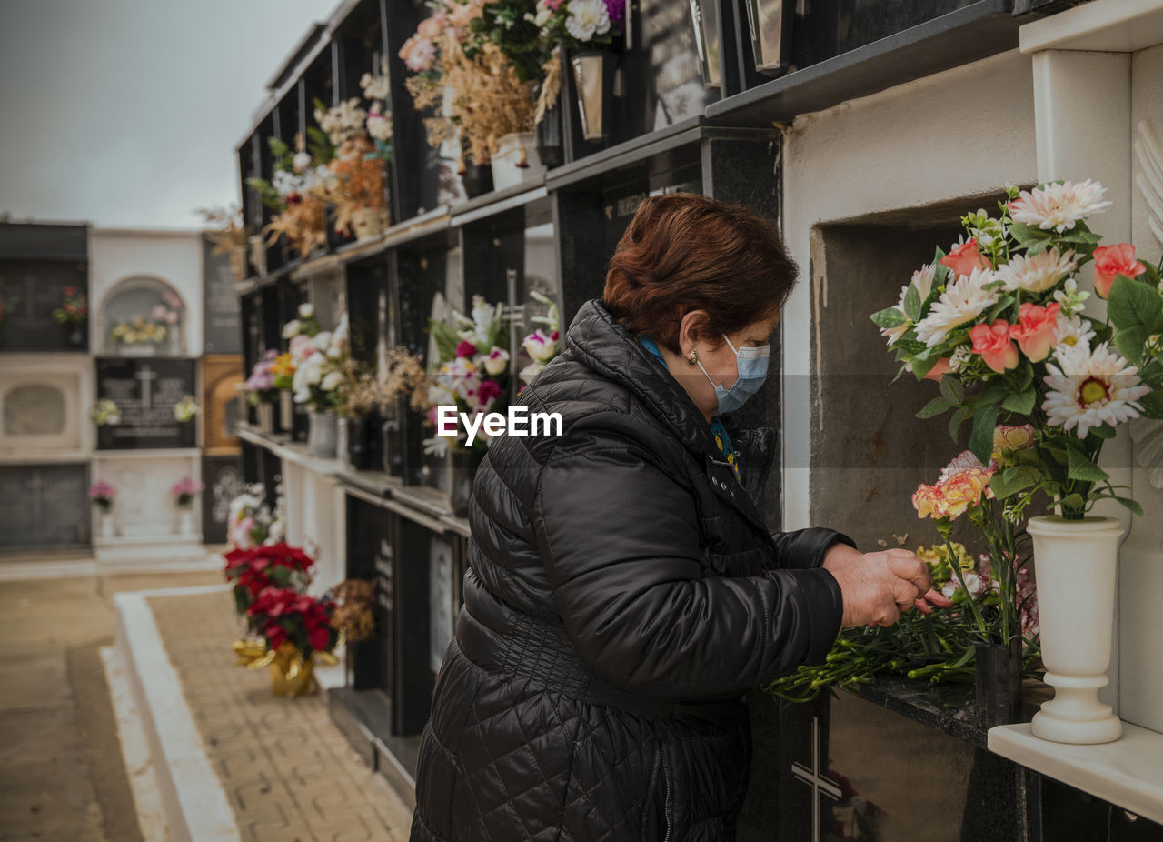 Old lady with mask mourning her family in cemetery. almeria, spain